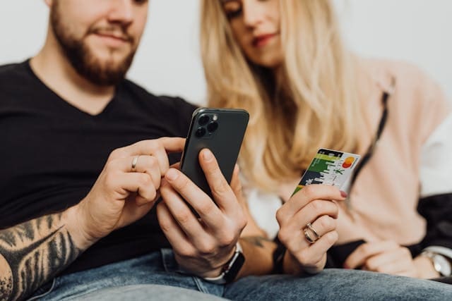 A couple using their mobile phone to purchase something with their mastercard